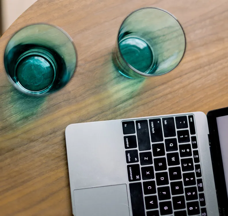 Table with two glasses of water and a laptop.