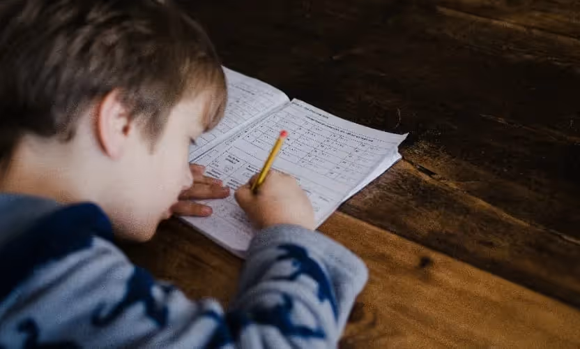 A child writing on a piece of paper with a pencil