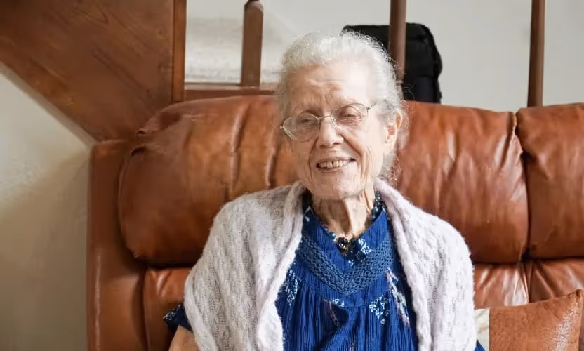 An elderly woman sitting and smiling