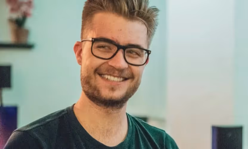 A young man in glasses smiling