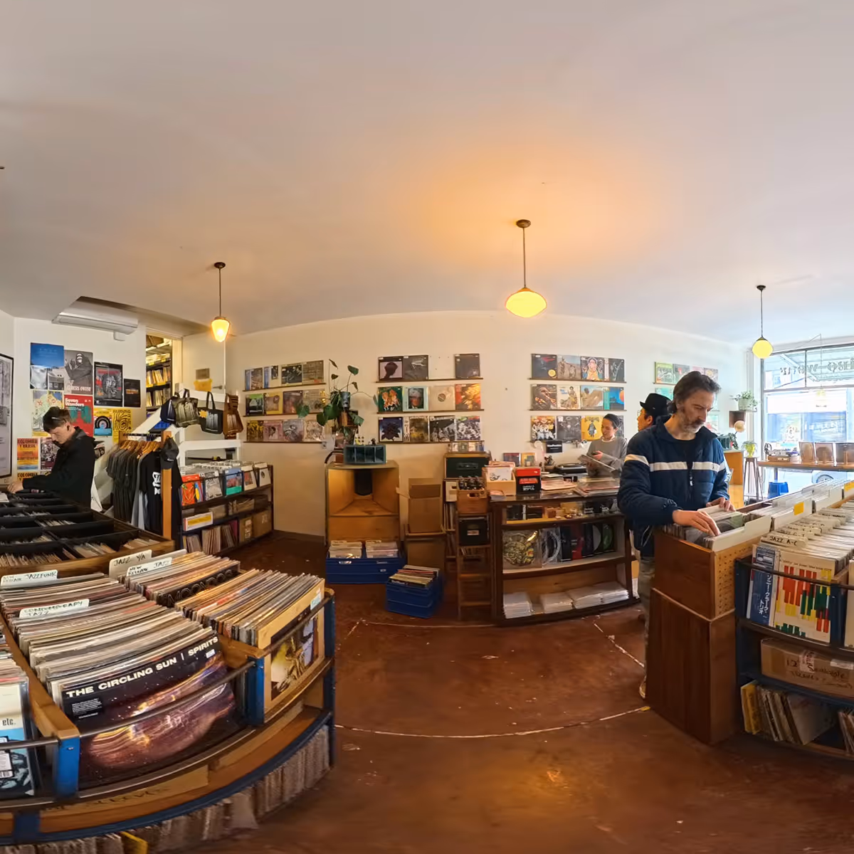 Interior of a cozy record store with vinyl records on shelves and walls, and people browsing collections.