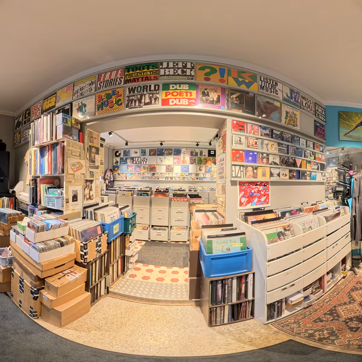 Interior of a cozy record store filled with vinyl albums, CDs, and posters on the walls.