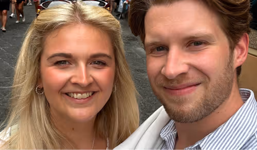 Close-up of a smiling young woman with blonde hair and a bearded man with light brown hair.
