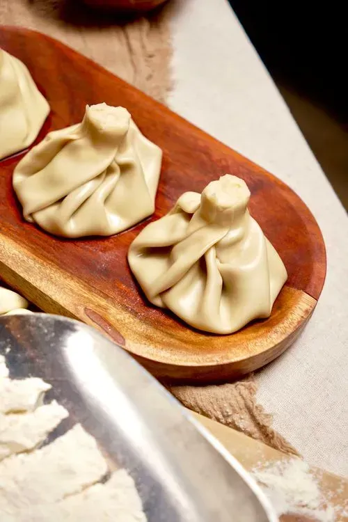 Classic boiled khinkali dumplings filled with spiced beef, displayed on a wooden serving dish.