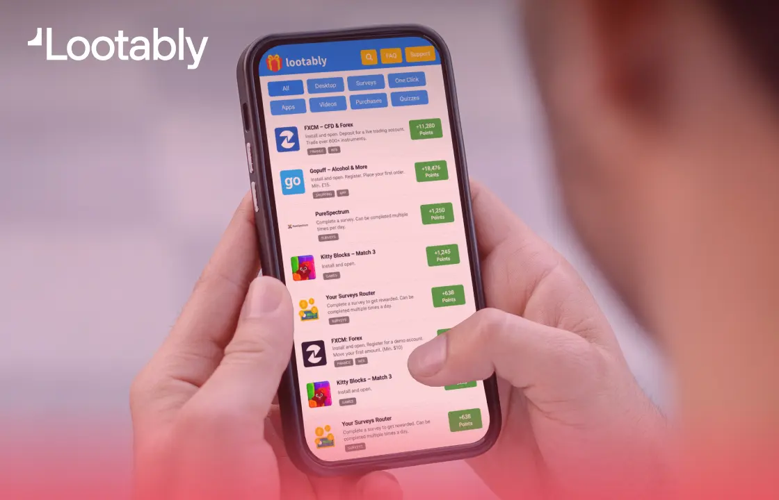 A person holding a smartphone displaying the Lootably app, with a list of offers, surveys, and games that reward users with points.