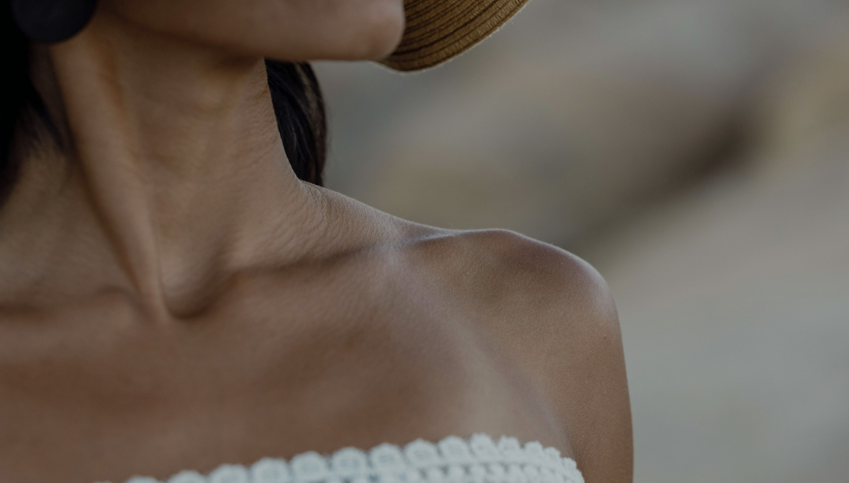 A woman with freckles and spots on her skin is looking on her shoulder 