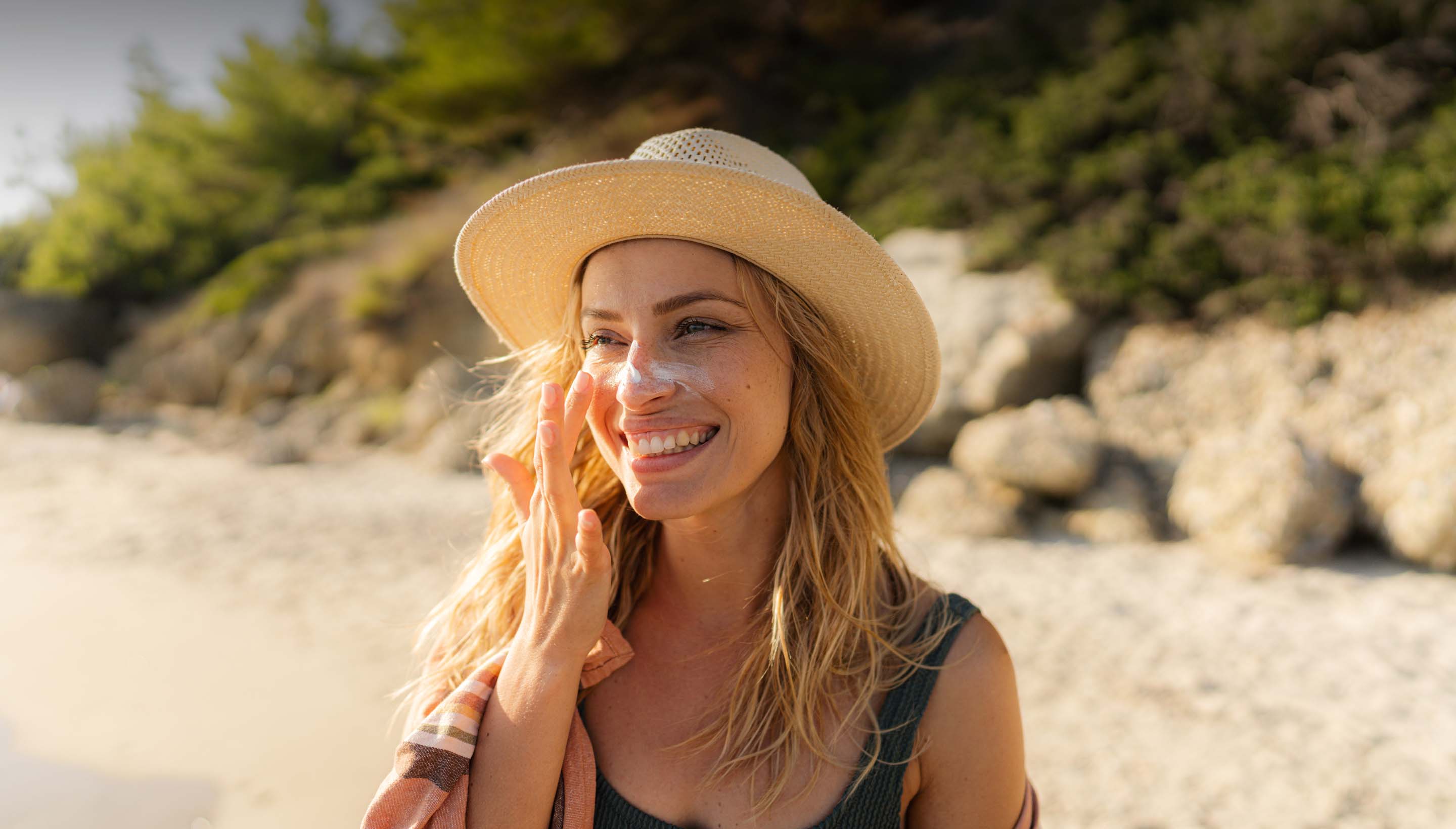 A woman at the beach applying sunscreen.