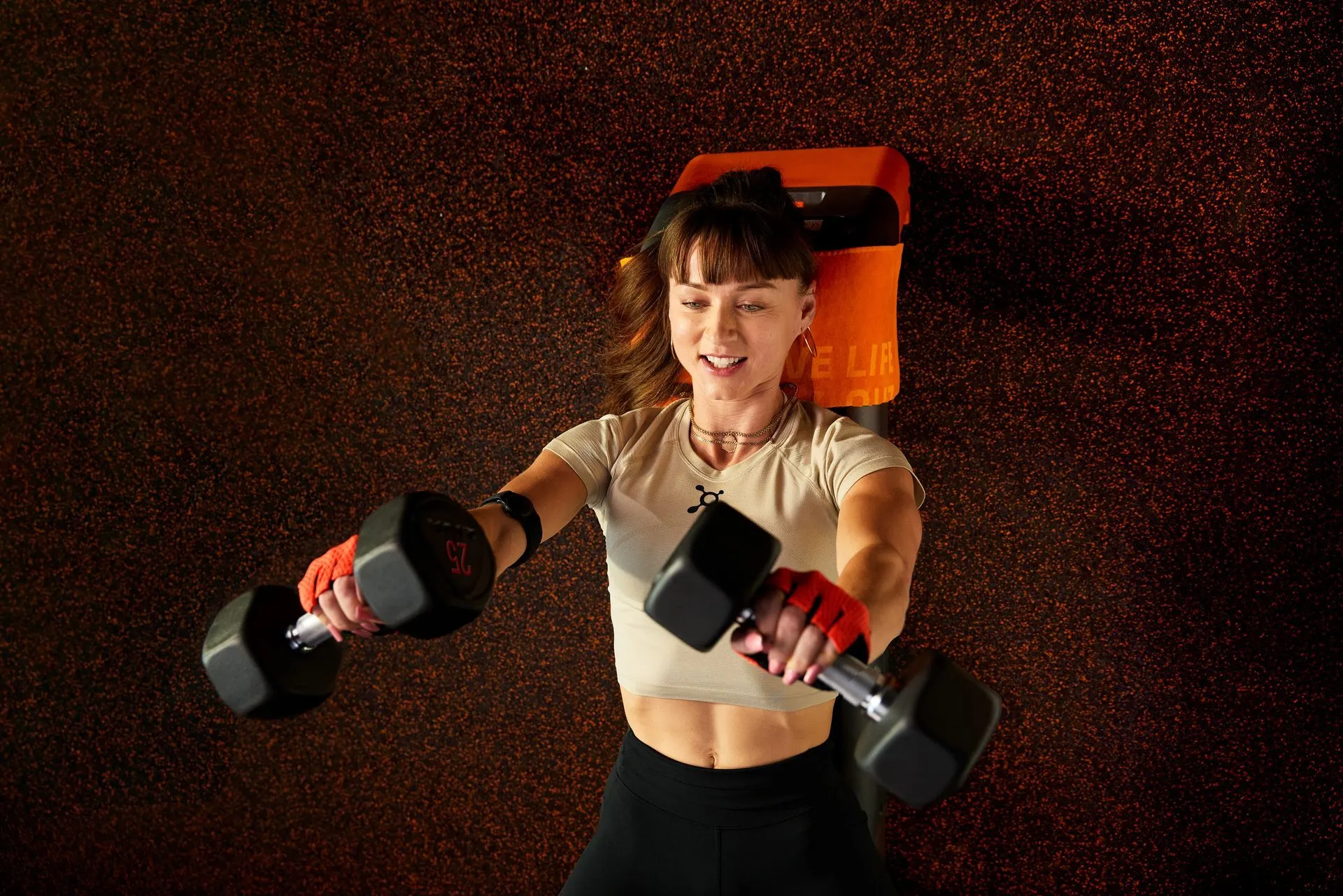 Woman in her mid-30s bench pressing dumbbells