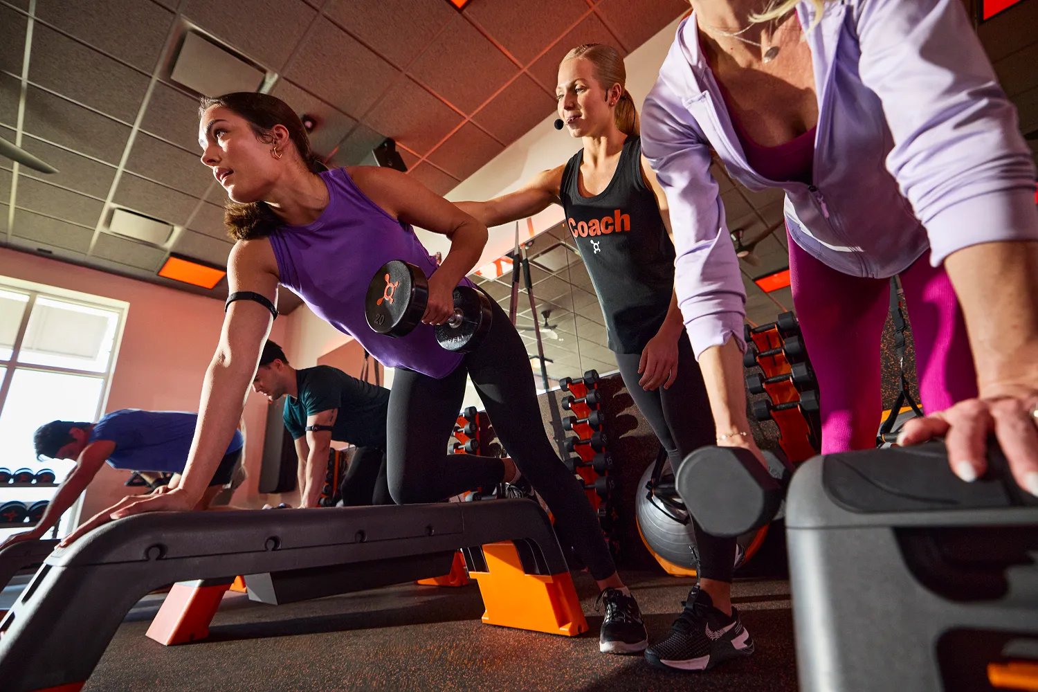Woman doing a low row with a dumbbell, guided by a coach.