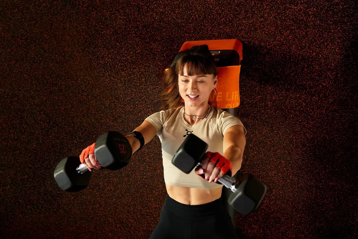 Woman in her mid-30s bench pressing dumbbells