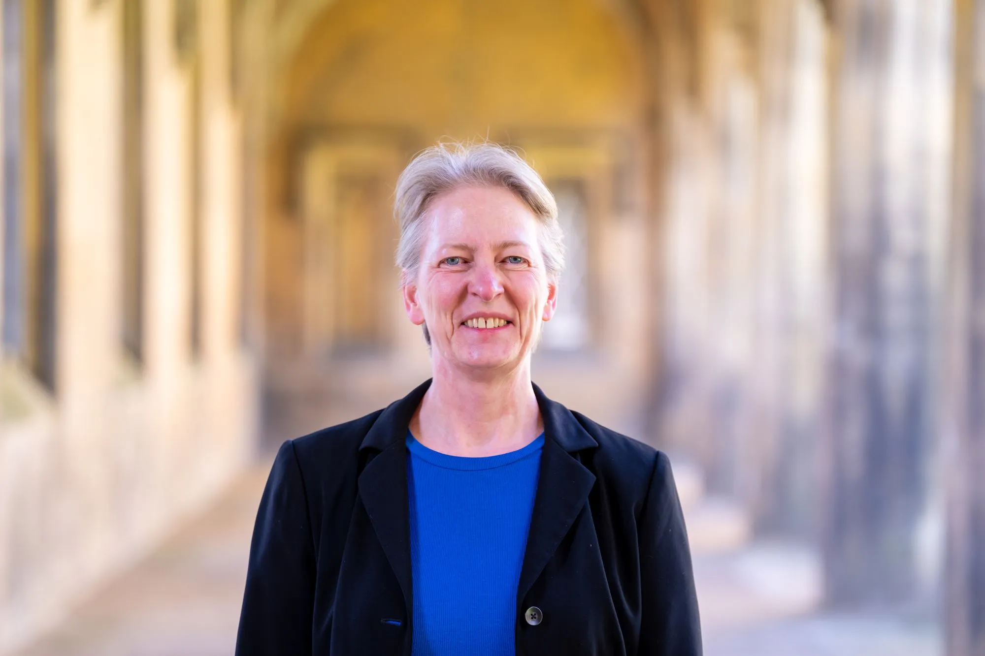 Dr Petra Geraats smiles at the camera in New Court Cloisters, St John's College