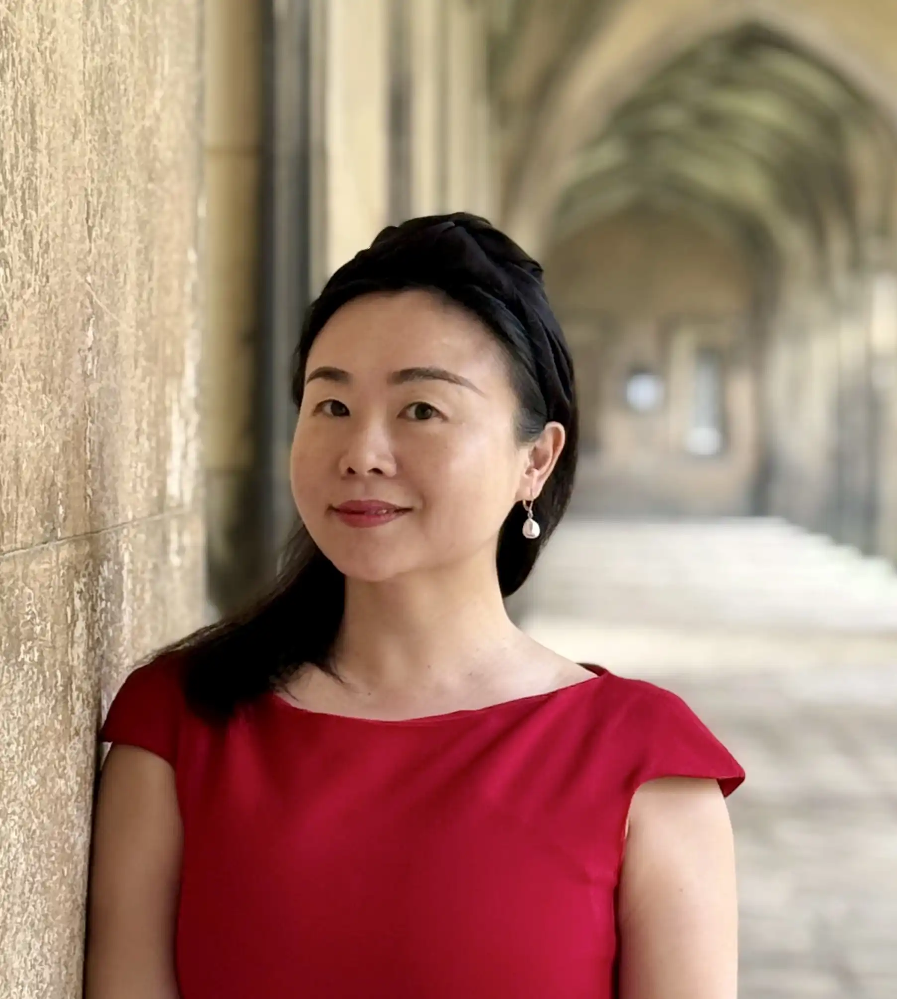 A portrait photograph of Jing Wang Thomas in The Cloisters of St John's College
