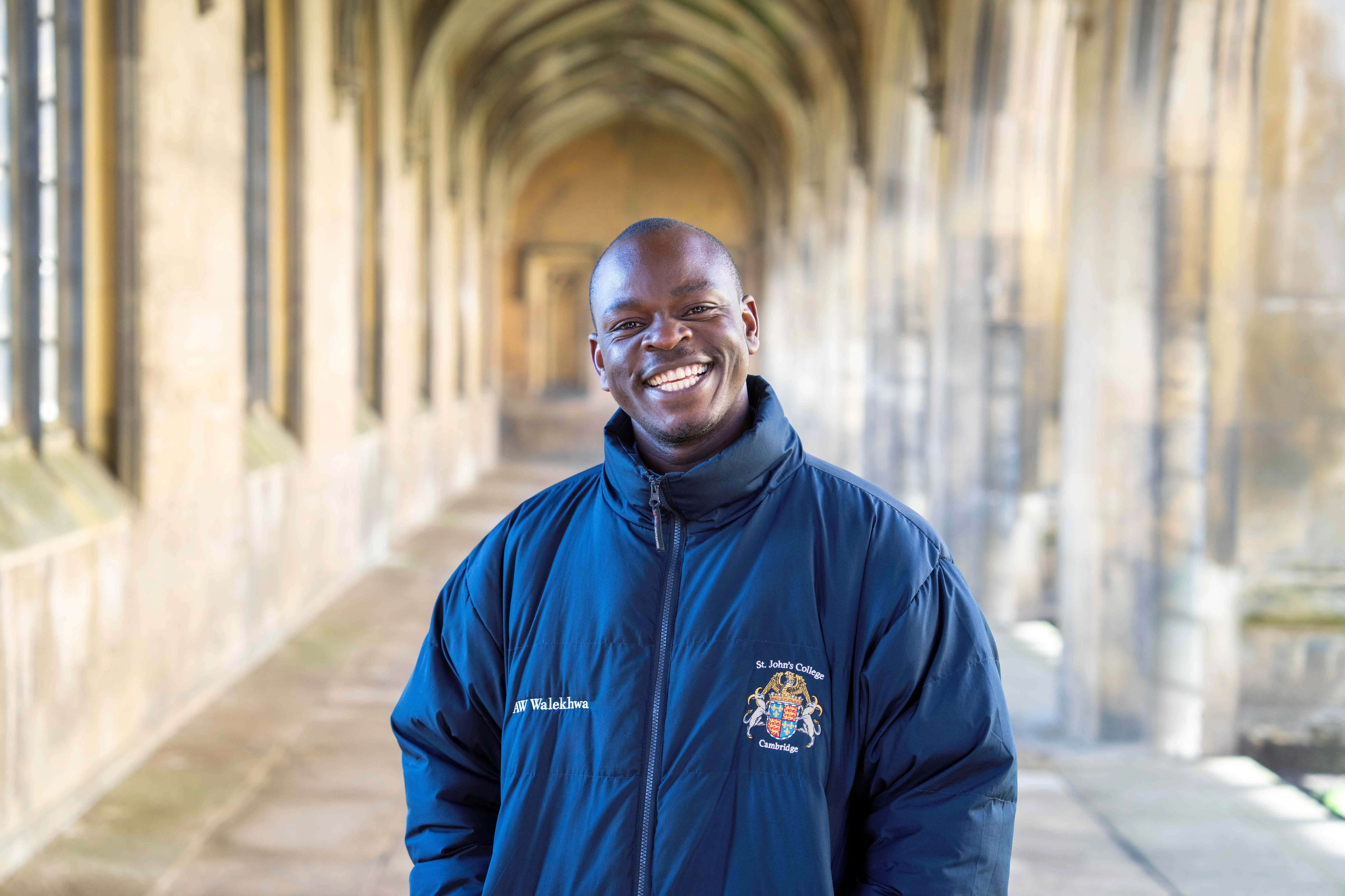 Ugandan PhD student Abel Wilson Walekhwa smiles at the camera in The Cloisters at St John's College, Cambridge
