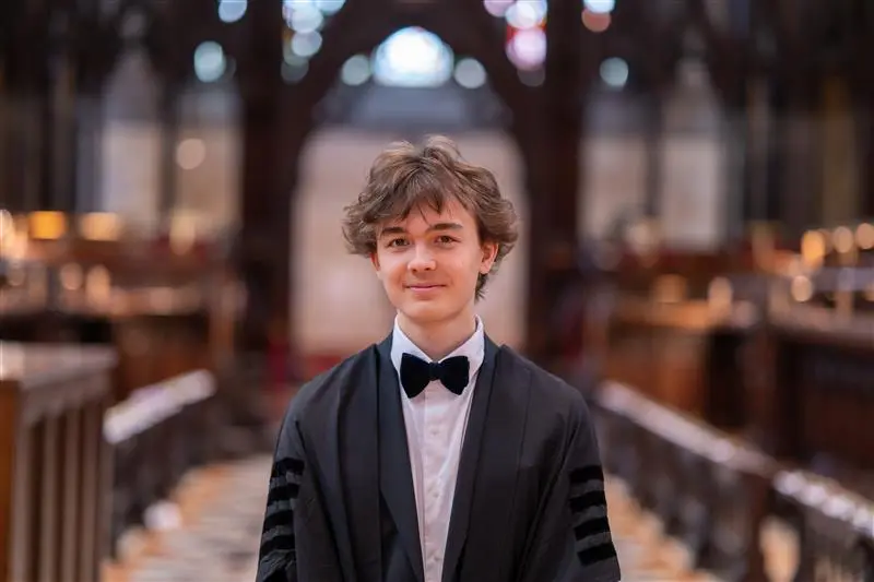 Pascal Bachmann standing in the chapel, looking directly at the camera, smiling.