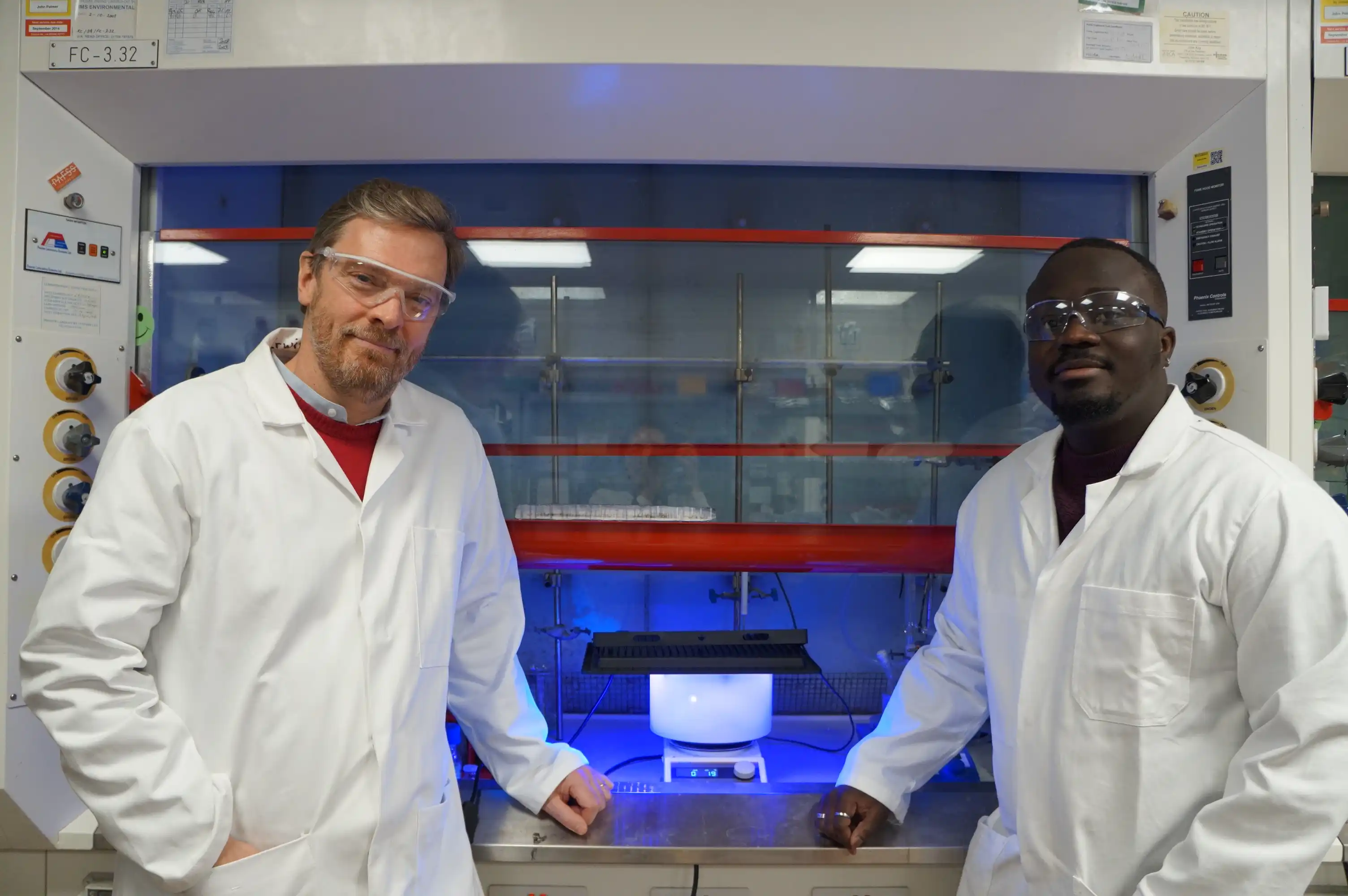 Two scientists in a laboratory stand either side of a device