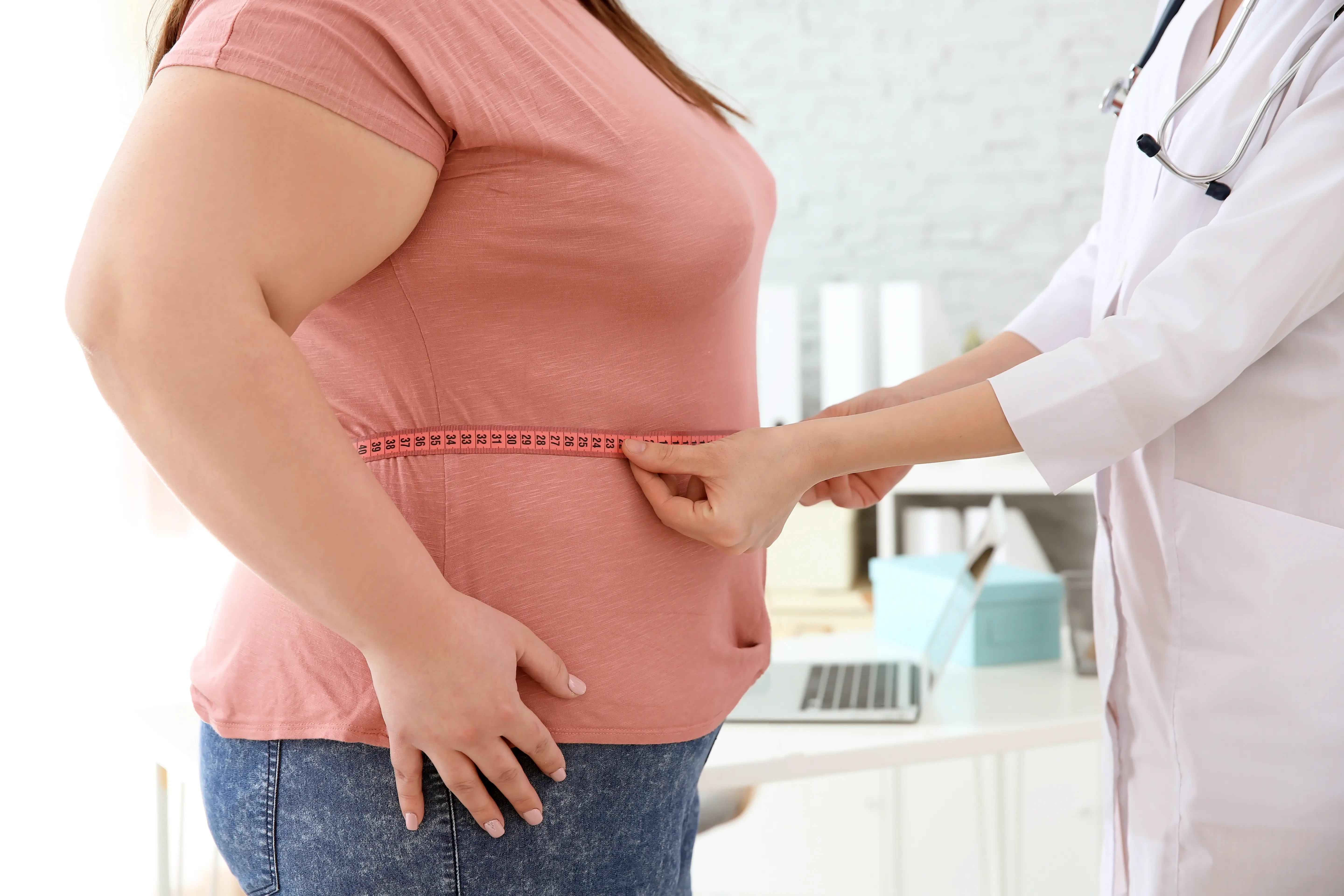 Doctor measures a woman's waist in a clinical setting