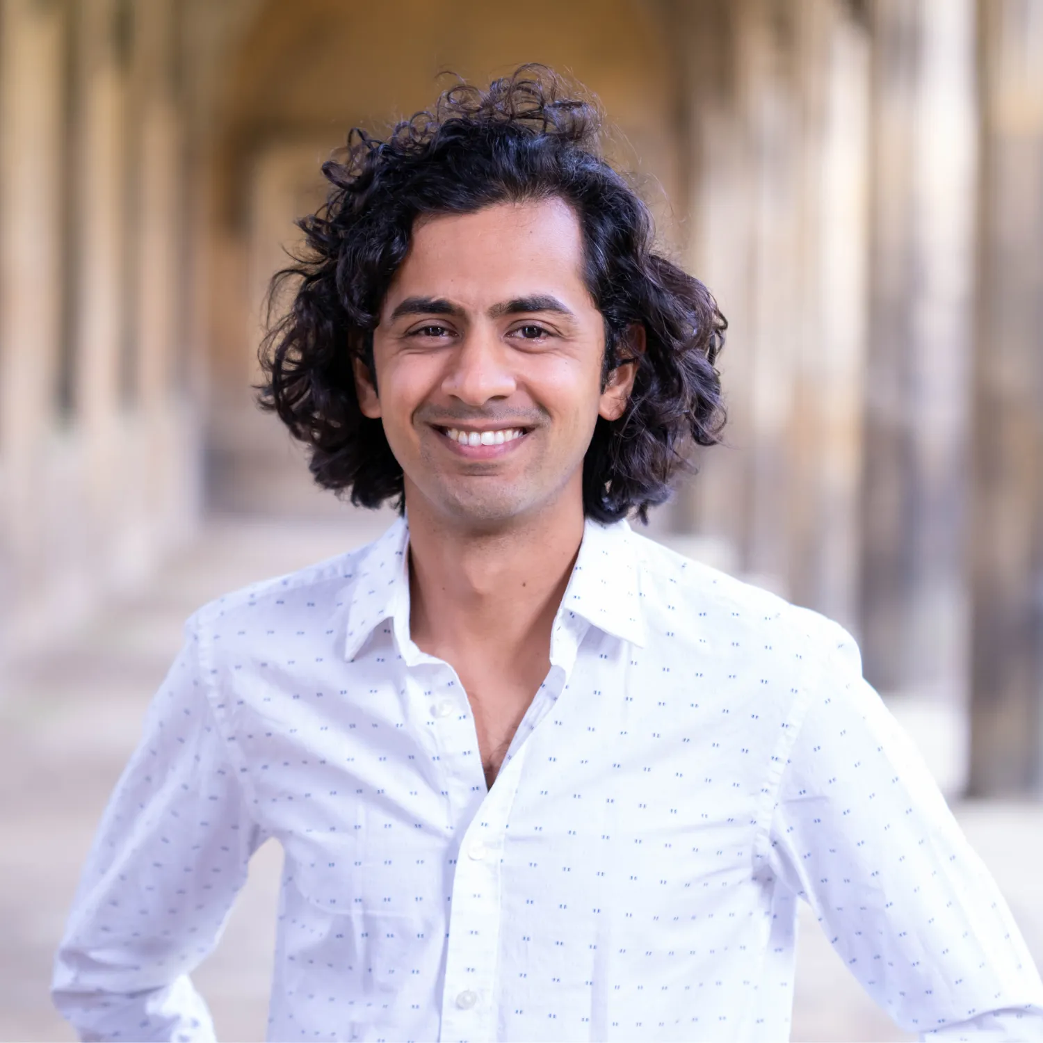 A portrait of Professor Dhruv Ranganathan in The Cloisters of St John's College, Cambridge