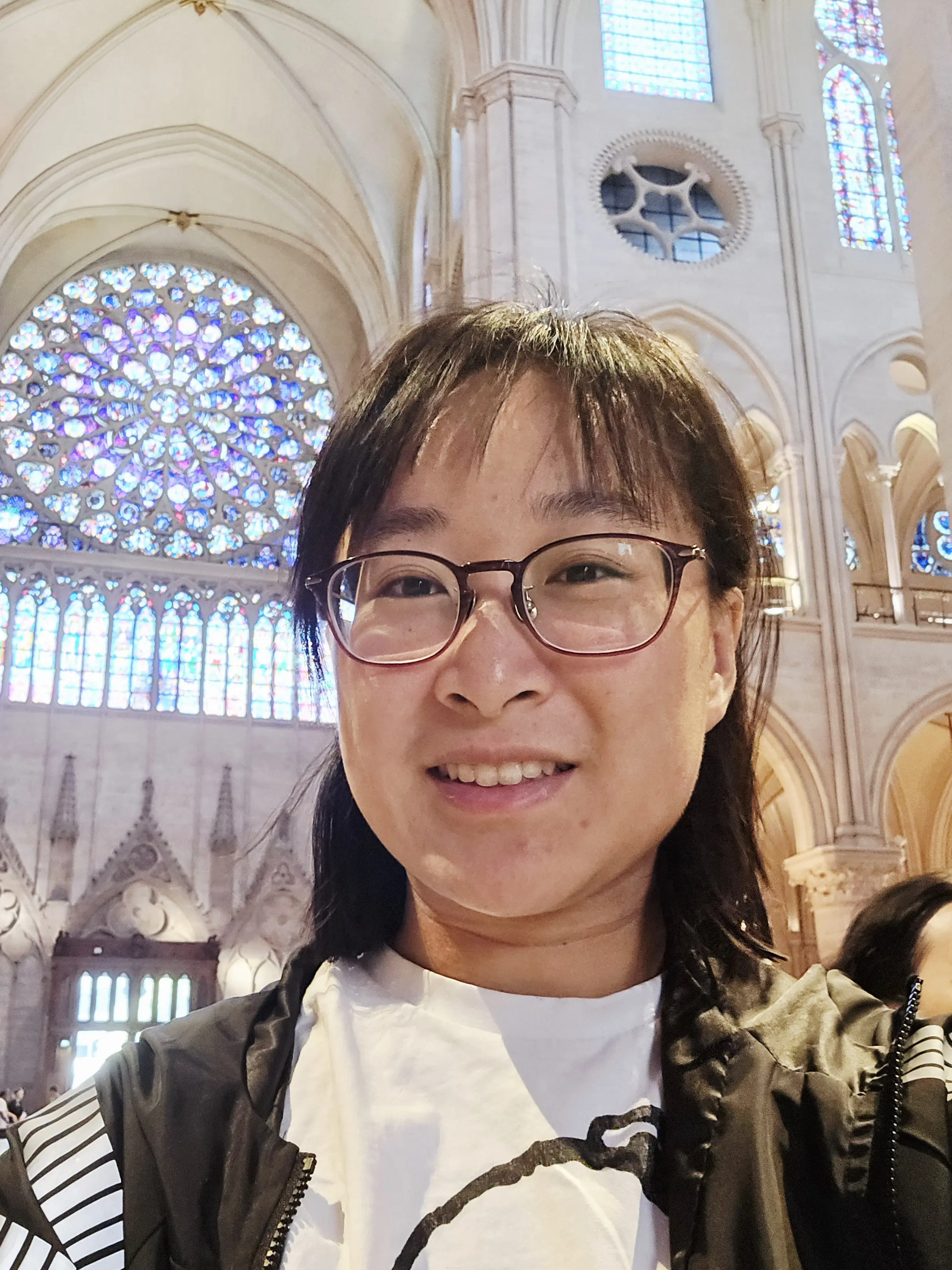 Dr Yeh stands in front of a large stained glass window looking into the camera.