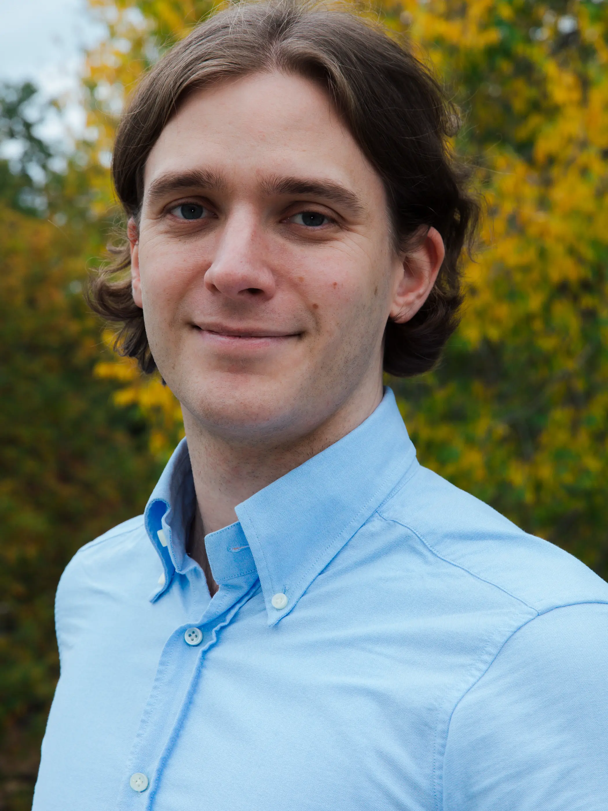 Dr Leo Leitzinger look directly into the camera smiling. He is wearing a blue shirt.