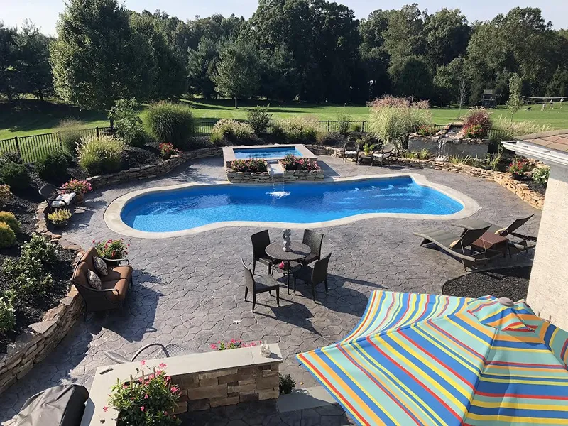 Backyard view of an in-ground pool with a hot tub.