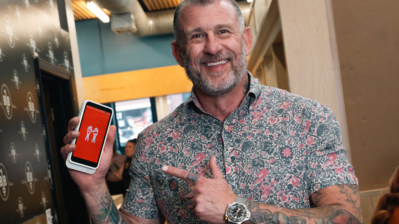 Tattoo shop owner pointing at the Porter card reader in a bright tattoo studio