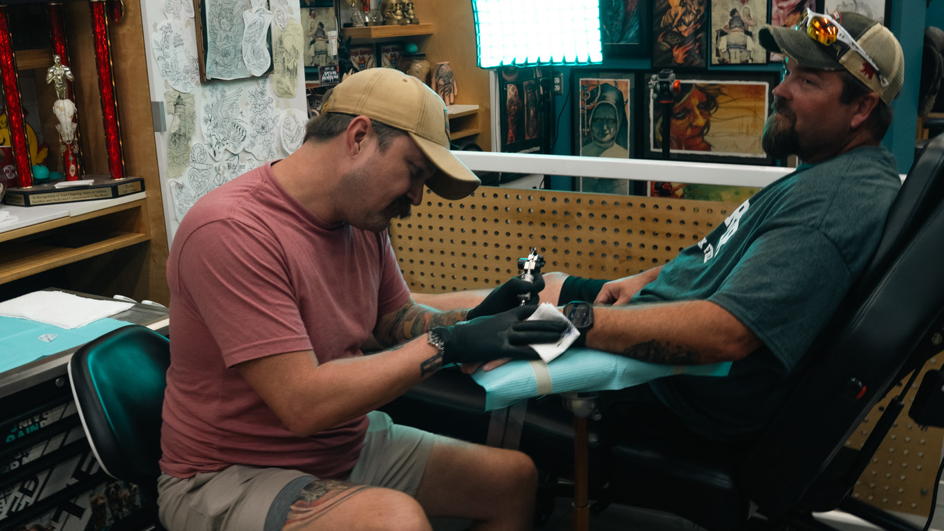Tattoo artist working on a client's forearm in a tattoo studio