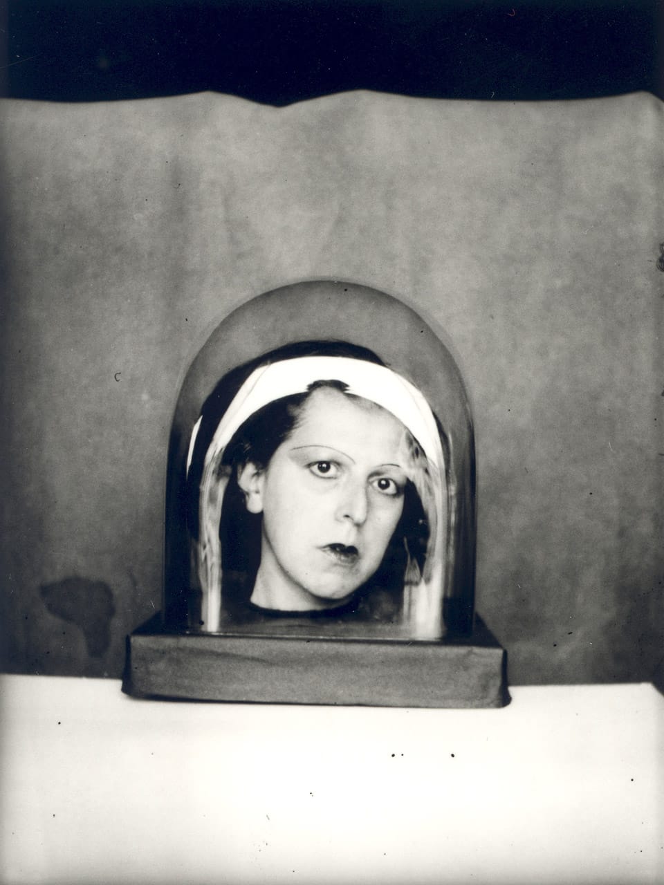 Claude Cahun self-portrait within glass dome, vintage monochrome style, Midjourney prompt engineering techniques, Studies For A Keepsake series (1925–1926).