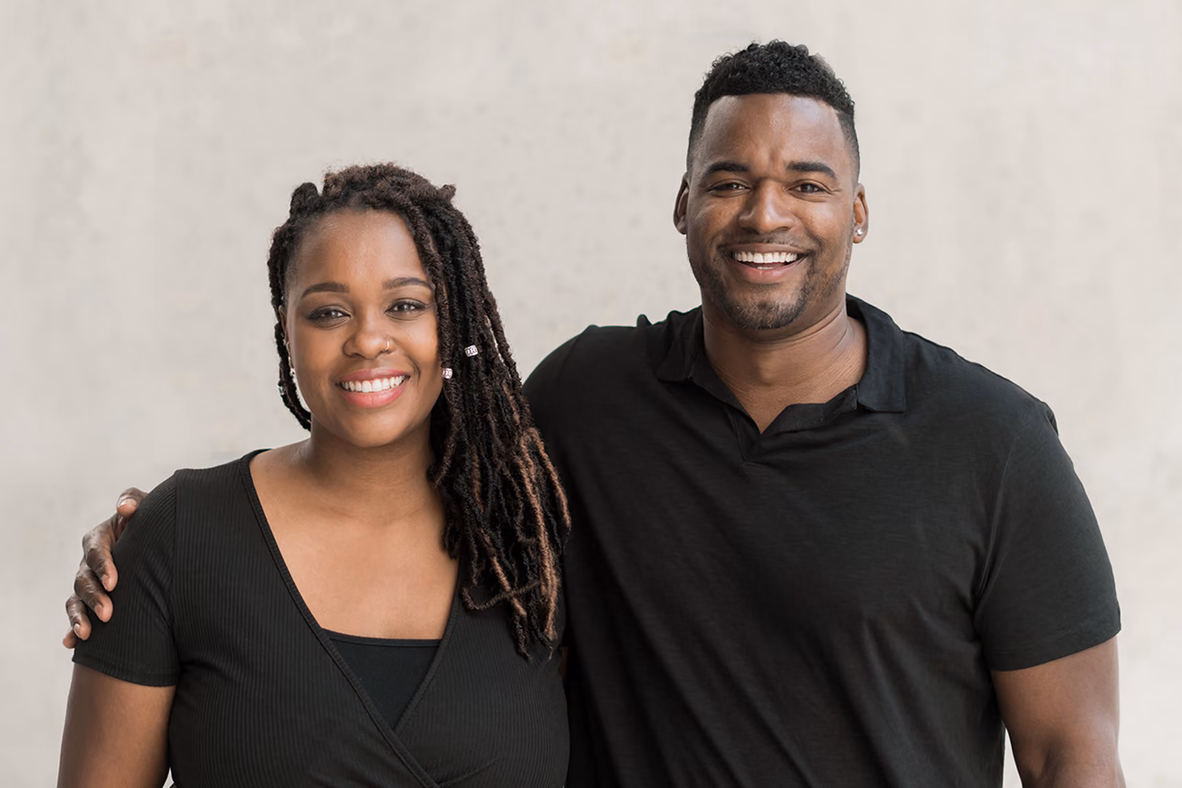 Malik and Ashley Edwards standing side by side, smiling, with his arm around her shoulder.