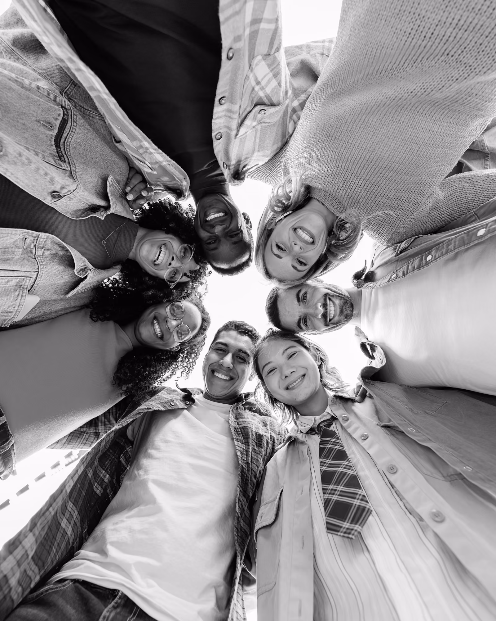 Happy diverse group of six young people in casual clothes smiling looking down at camera in a circle.