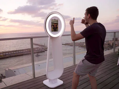 Gast posiert vor dem Videobooth auf einer Terrasse mit Meerblick bei Sonnenuntergang