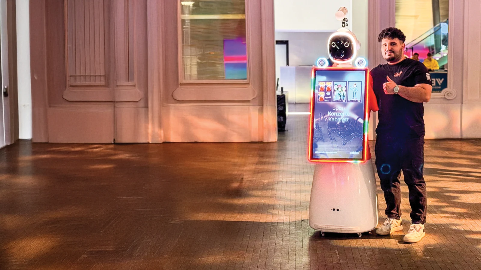 AI Fotobox Roboter LUNA im Festsaal, daneben ein FiestaPics-Mitarbeiter mit Fernsteuerung
