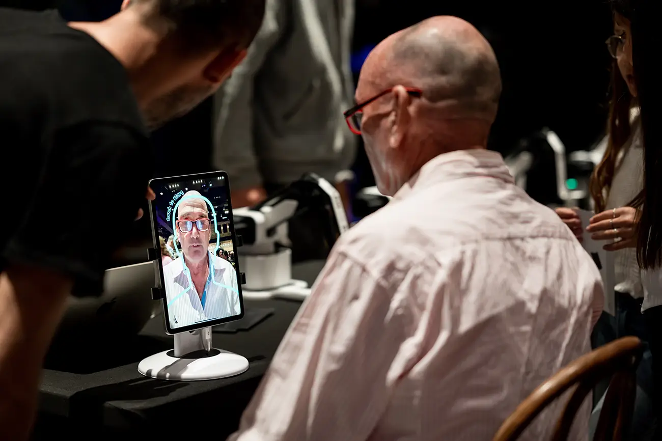 Guests at the AI Sketcher stand looking at the portrait on the tablet