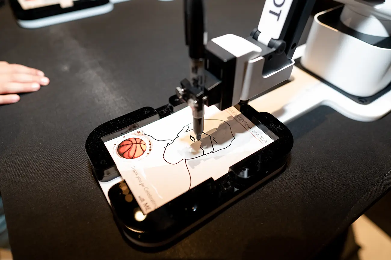 Robot arm drawing a portrait with a basketball on paper