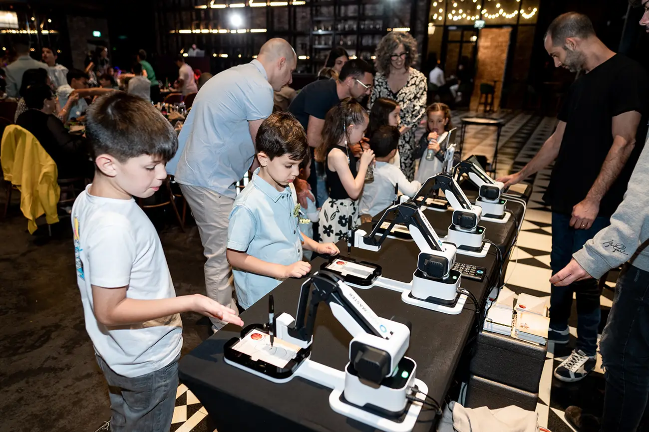 Guests and children queuing at the row of AI Sketcher robots