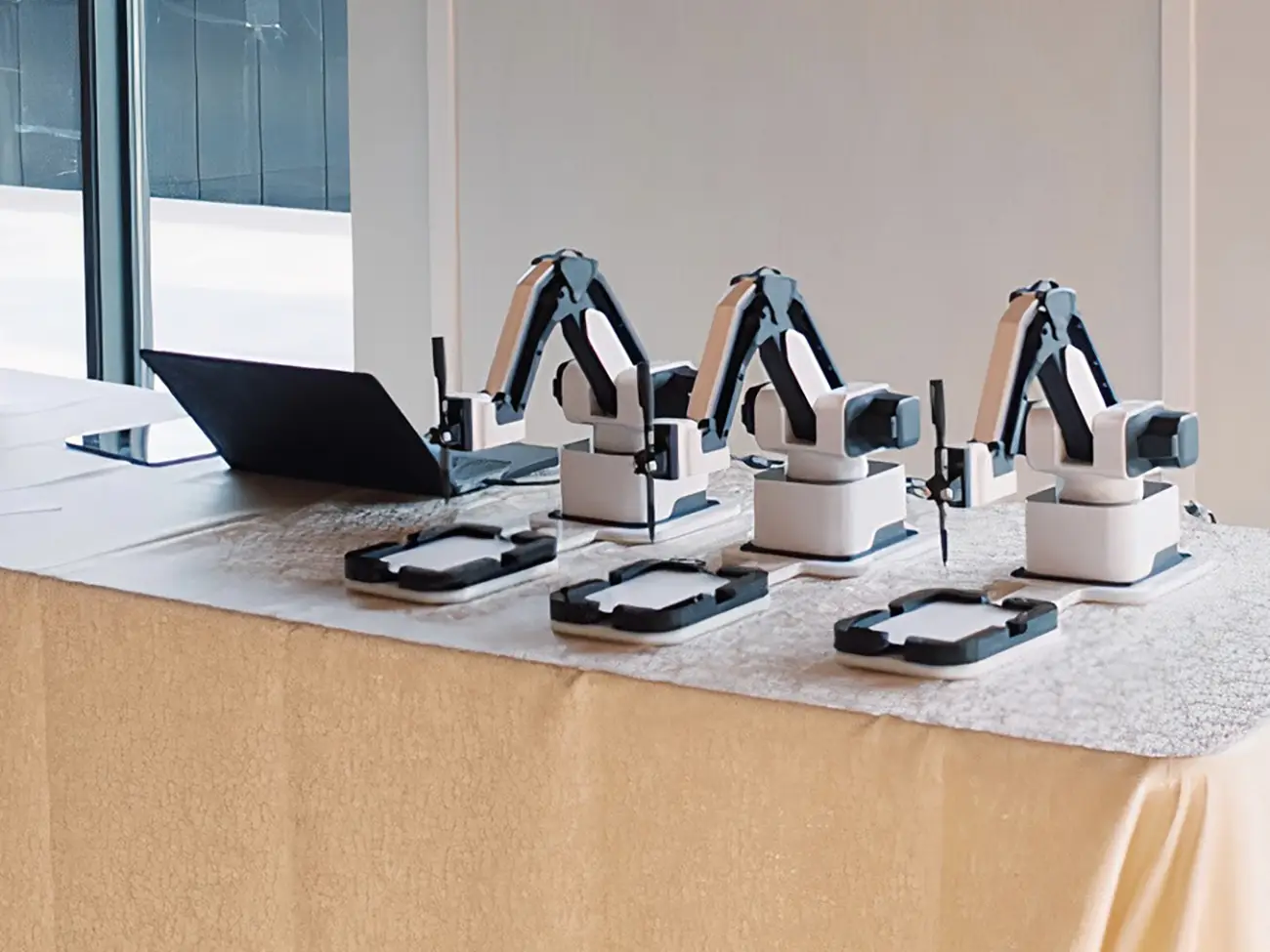 AI Sketcher robots on a table with a laptop in a bright room