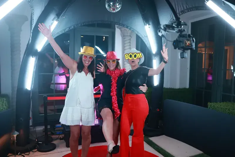 Three guests posing with props inside the 360 degree video booth