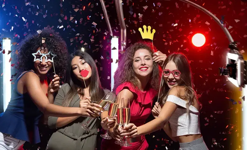 Four guests toasting in a shower of confetti against a red backdrop