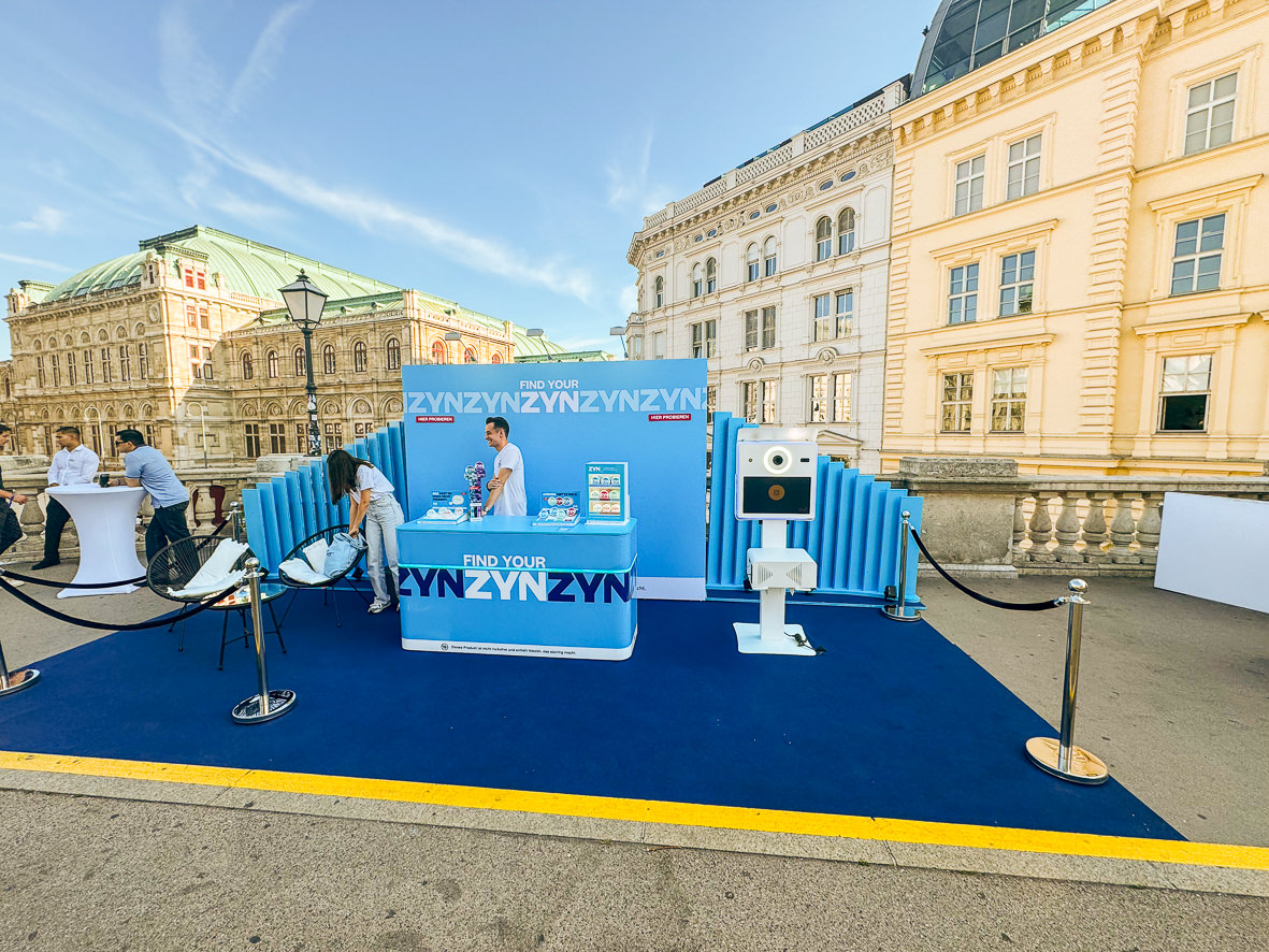Blue branded open air stand with a photo booth in front of the Vienna State Opera