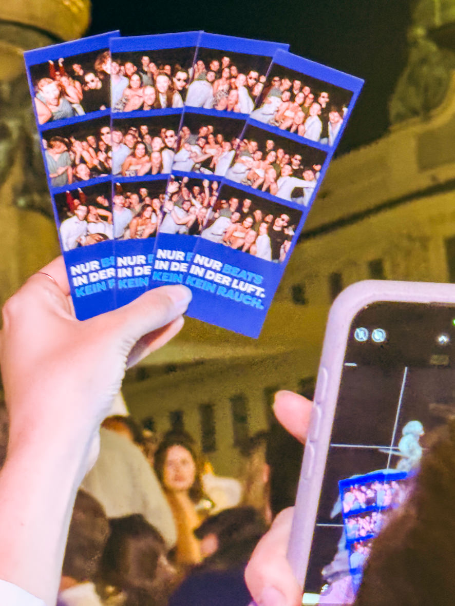 Several branded photo strips from the open air stand held in a hand