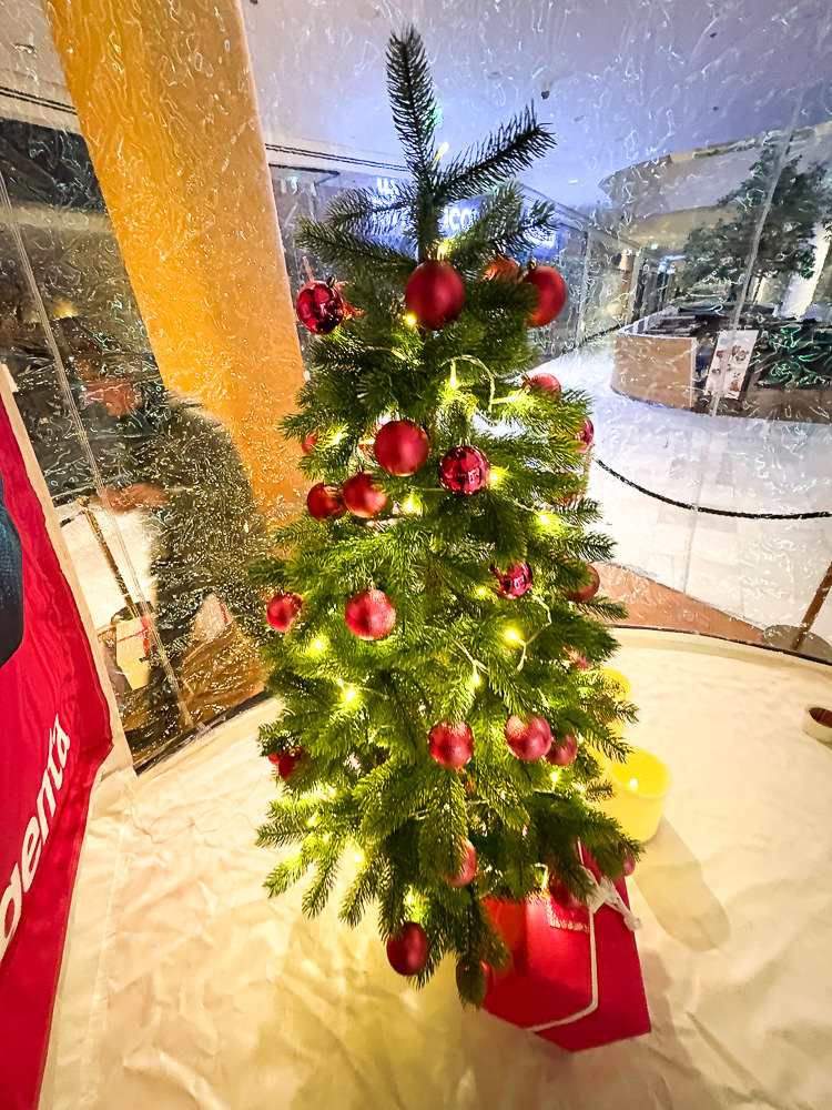 Geschmückter Christbaum neben der Schneekugel im Einkaufszentrum