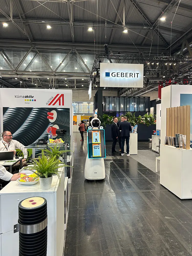 AI Fotobox Roboter LUNA zwischen den Ständen einer Messehalle