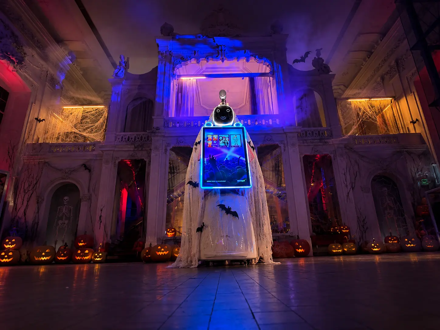 Fotobox Roboter LUNA im Geist-Kostüm zwischen Kürbissen und Nebel für Halloween-Deko