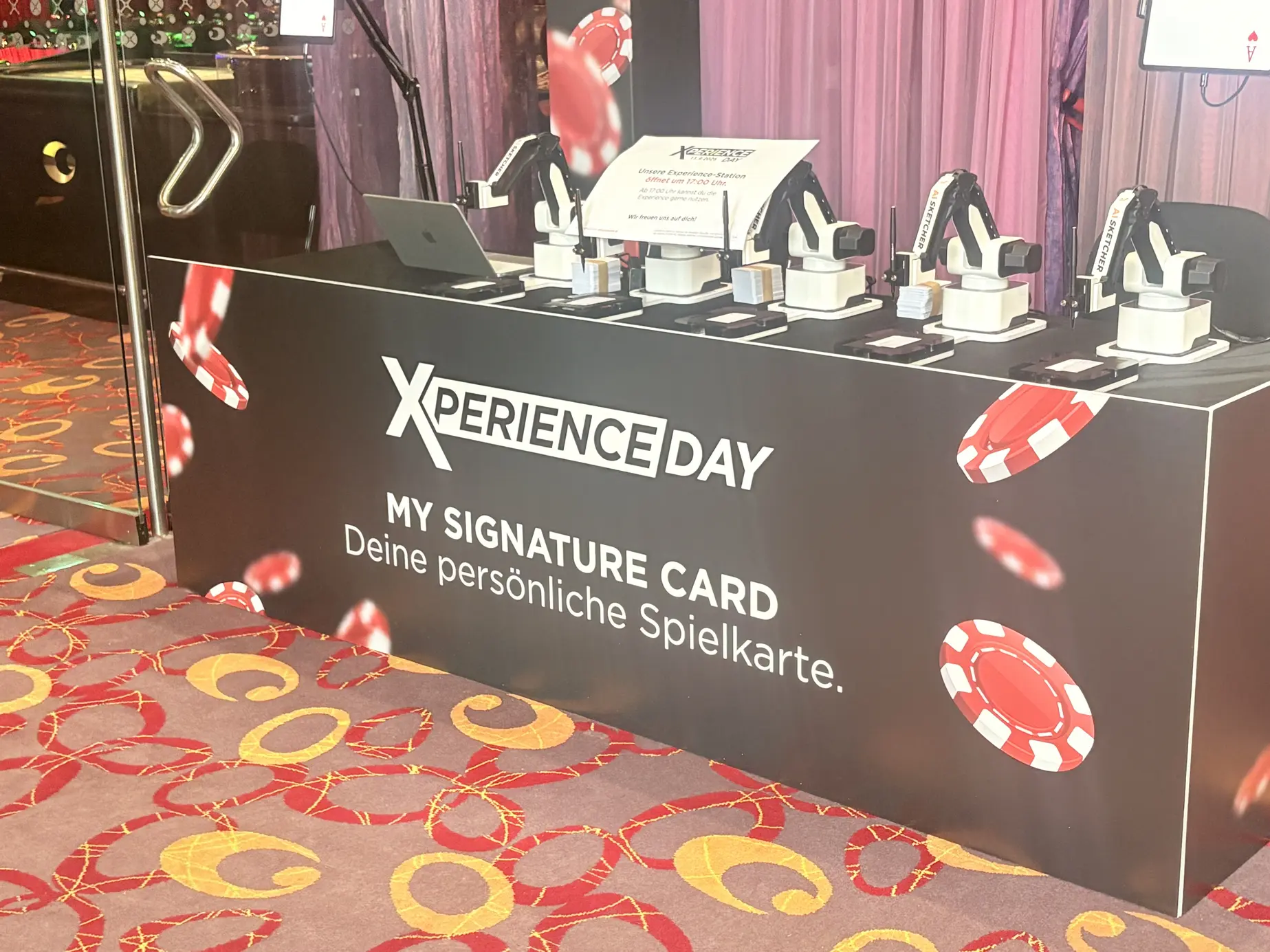 AI Sketcher mit fünf Roboterarmen am gebrandeten XPERIENCE DAY Counter im Casino Baden