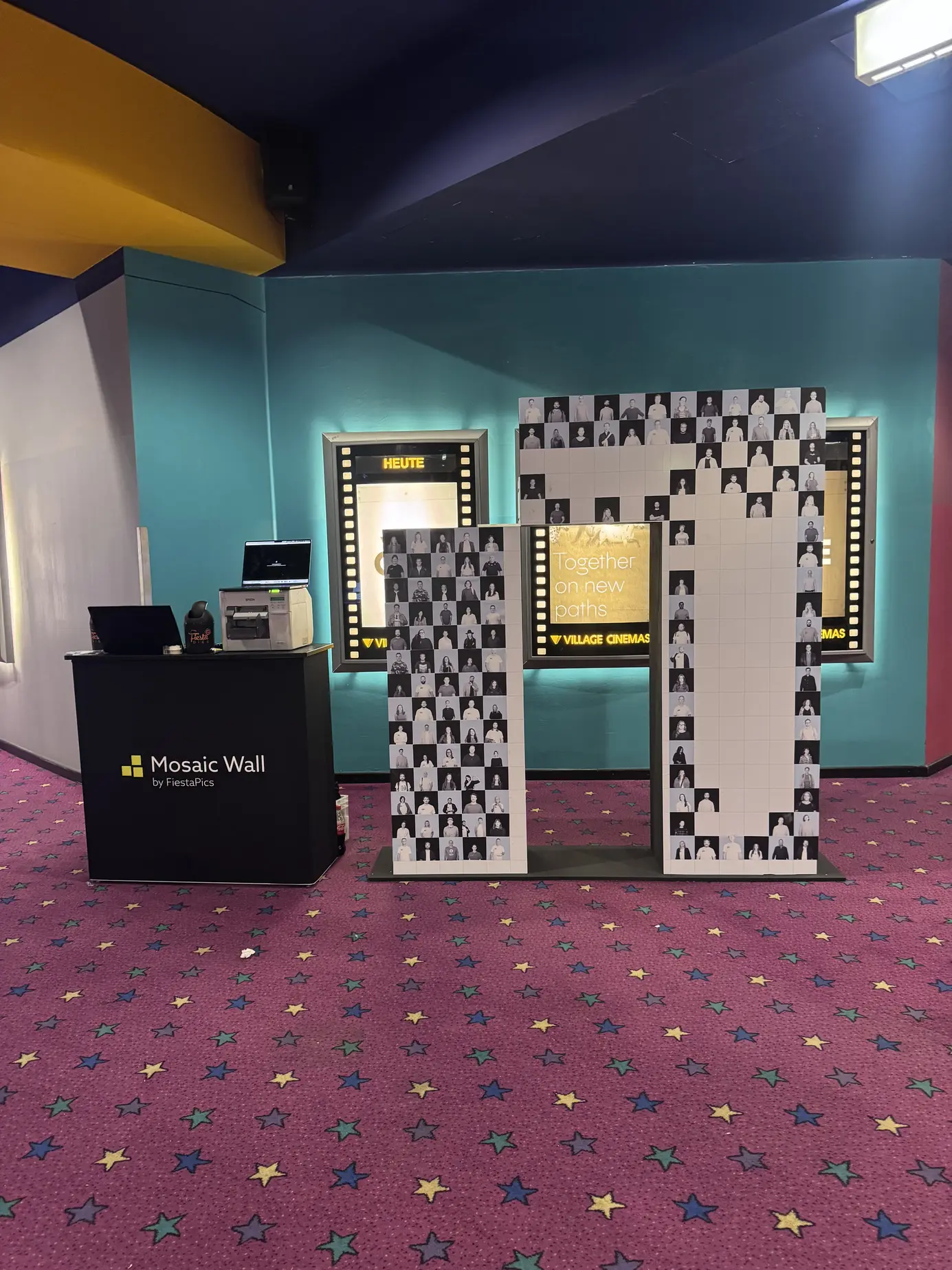 Die ersten Fotokacheln auf dem norika-Logo im Foyer des Village Cinema