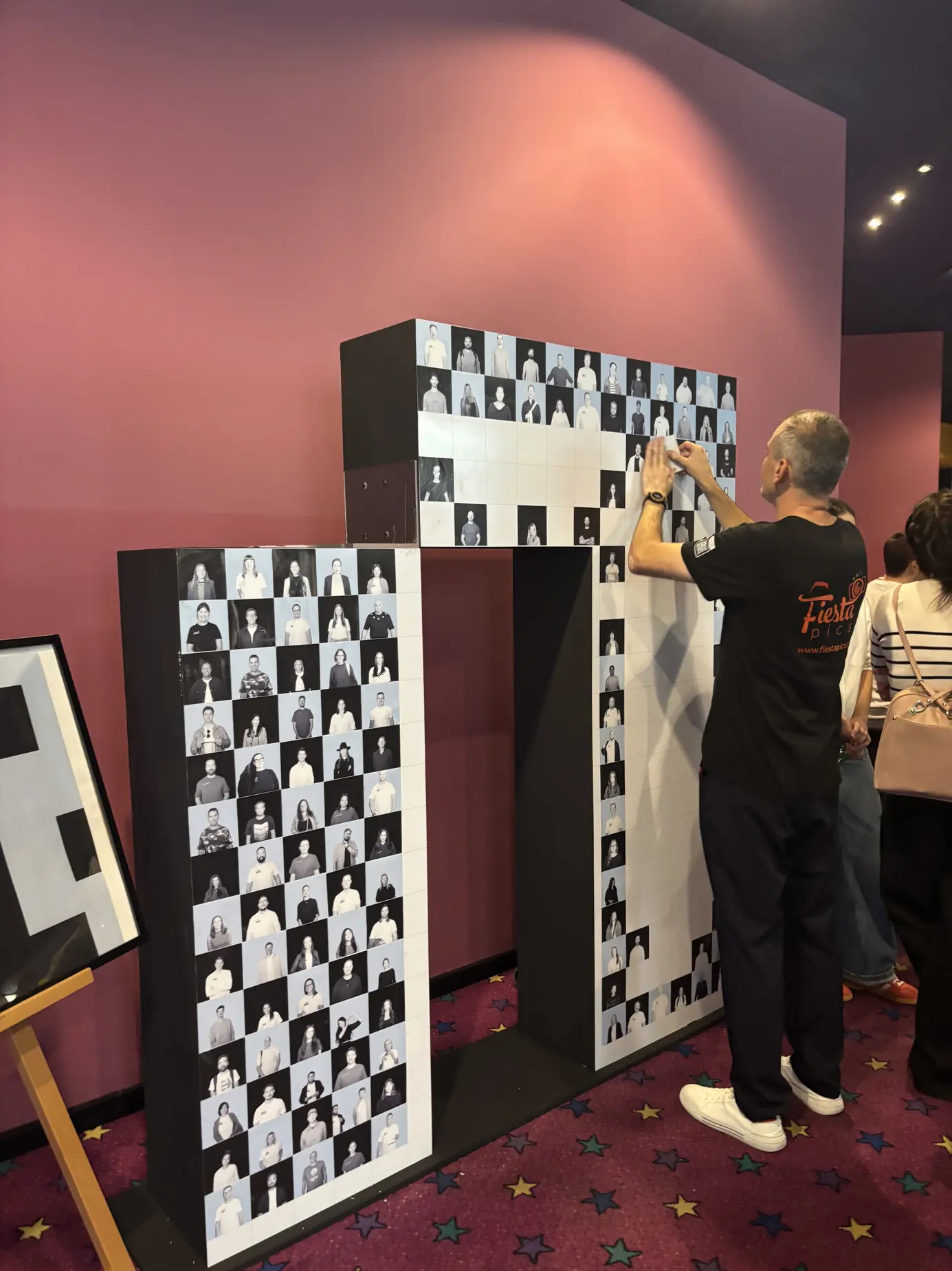 FiestaPics-Mitarbeiter klebt Schwarzweiß-Porträts auf den 3D-Buchstaben N