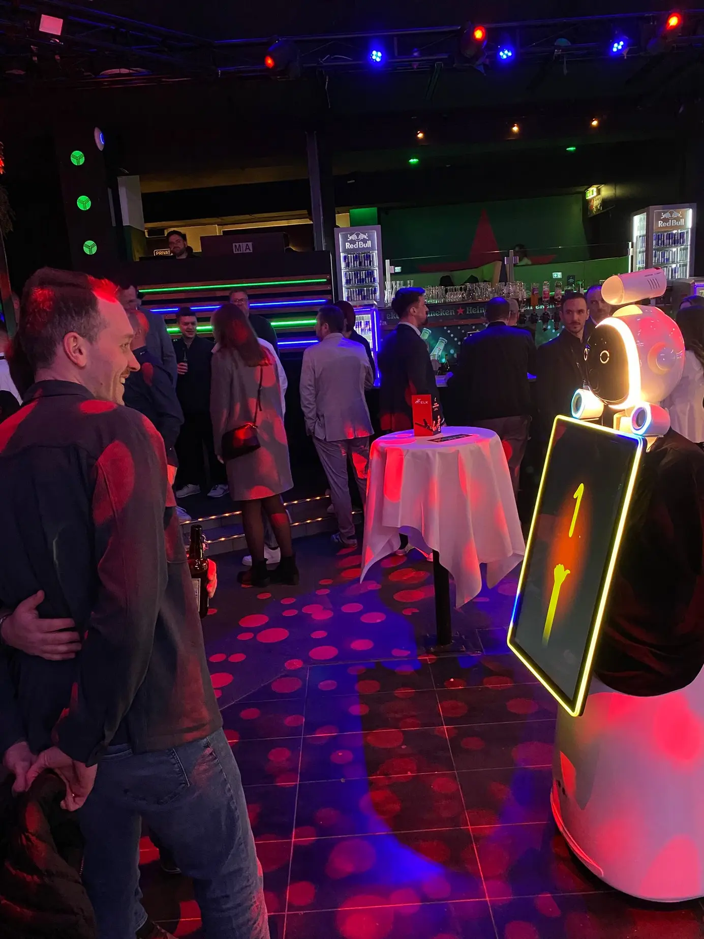 AI Fotobox Roboter LUNA im ELK-Shirt zwischen Gästen in der Discothek Ypsilon beim ELK Future Summit 2026