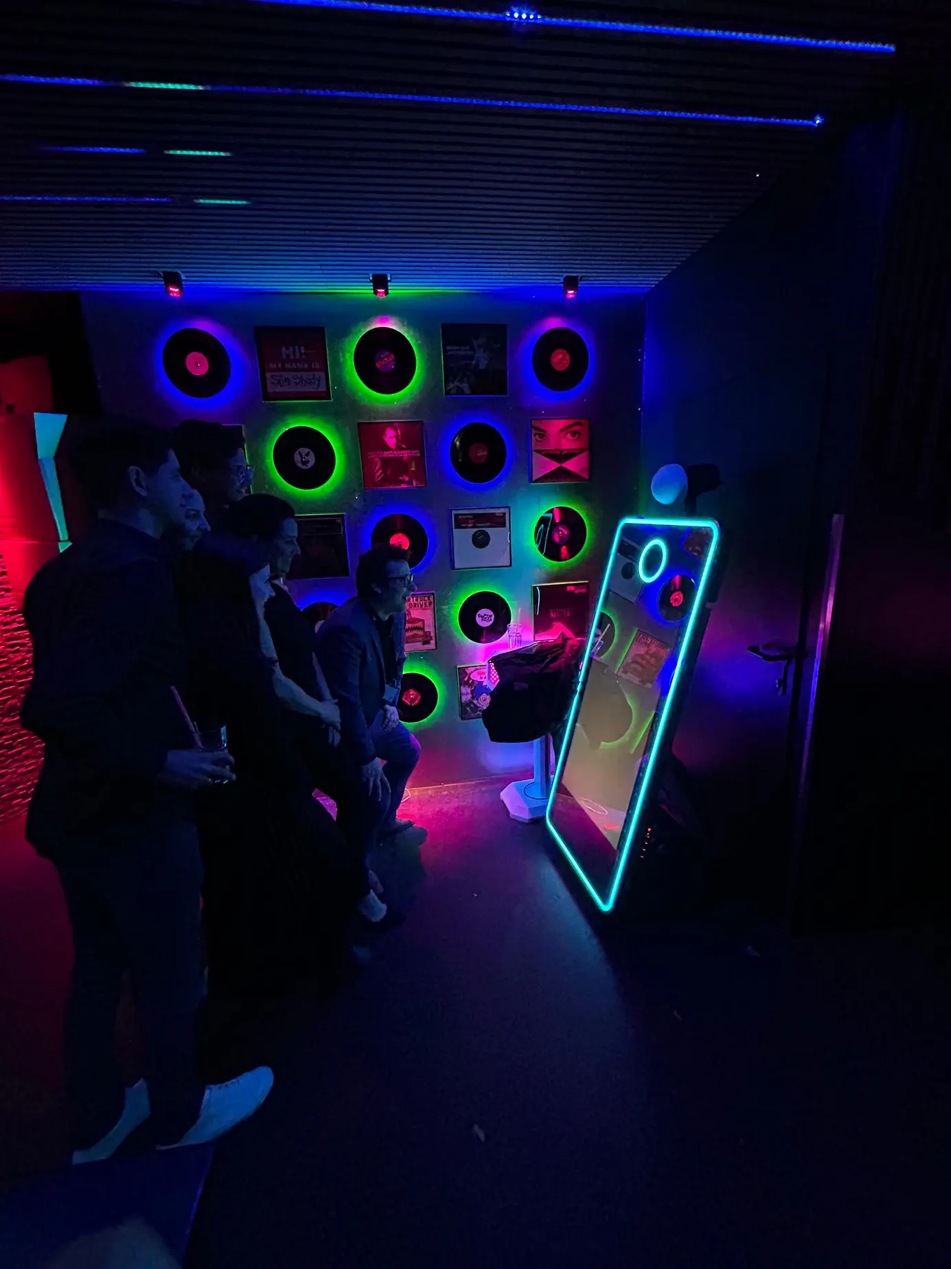 Gruppe wartet im blauen Licht vor dem iMirror auf ihr Bild