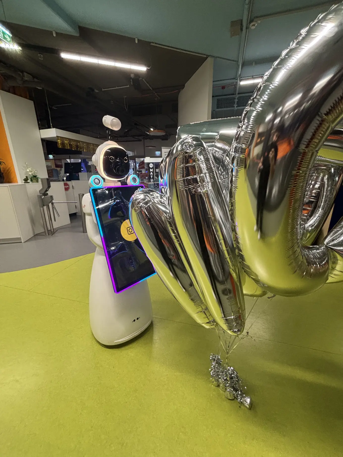 Der Fotobox Roboter neben einem großen silbernen Zahlenballon