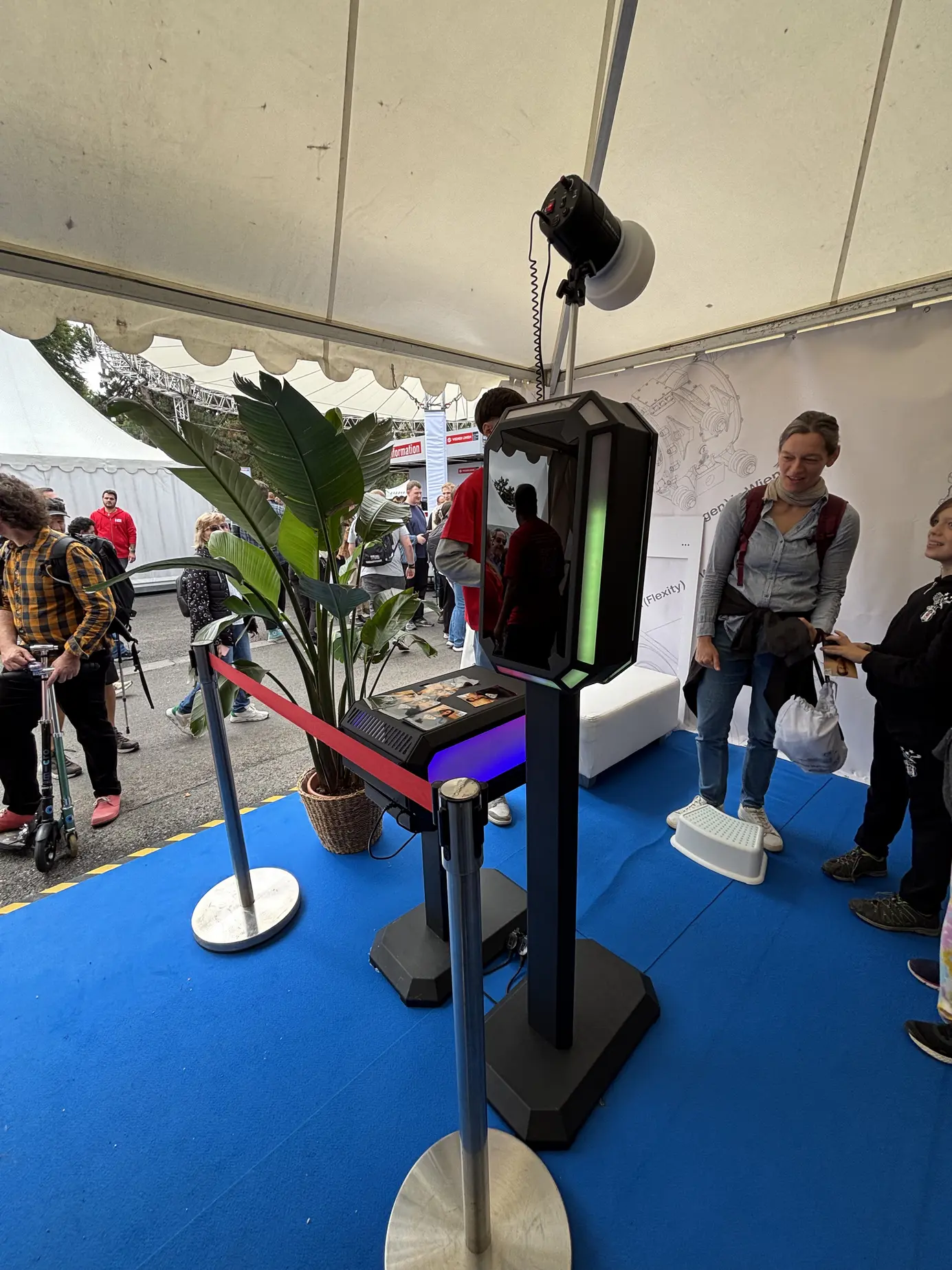 Besucherin vor der beleuchteten KI Fotobox am offenen Messestand