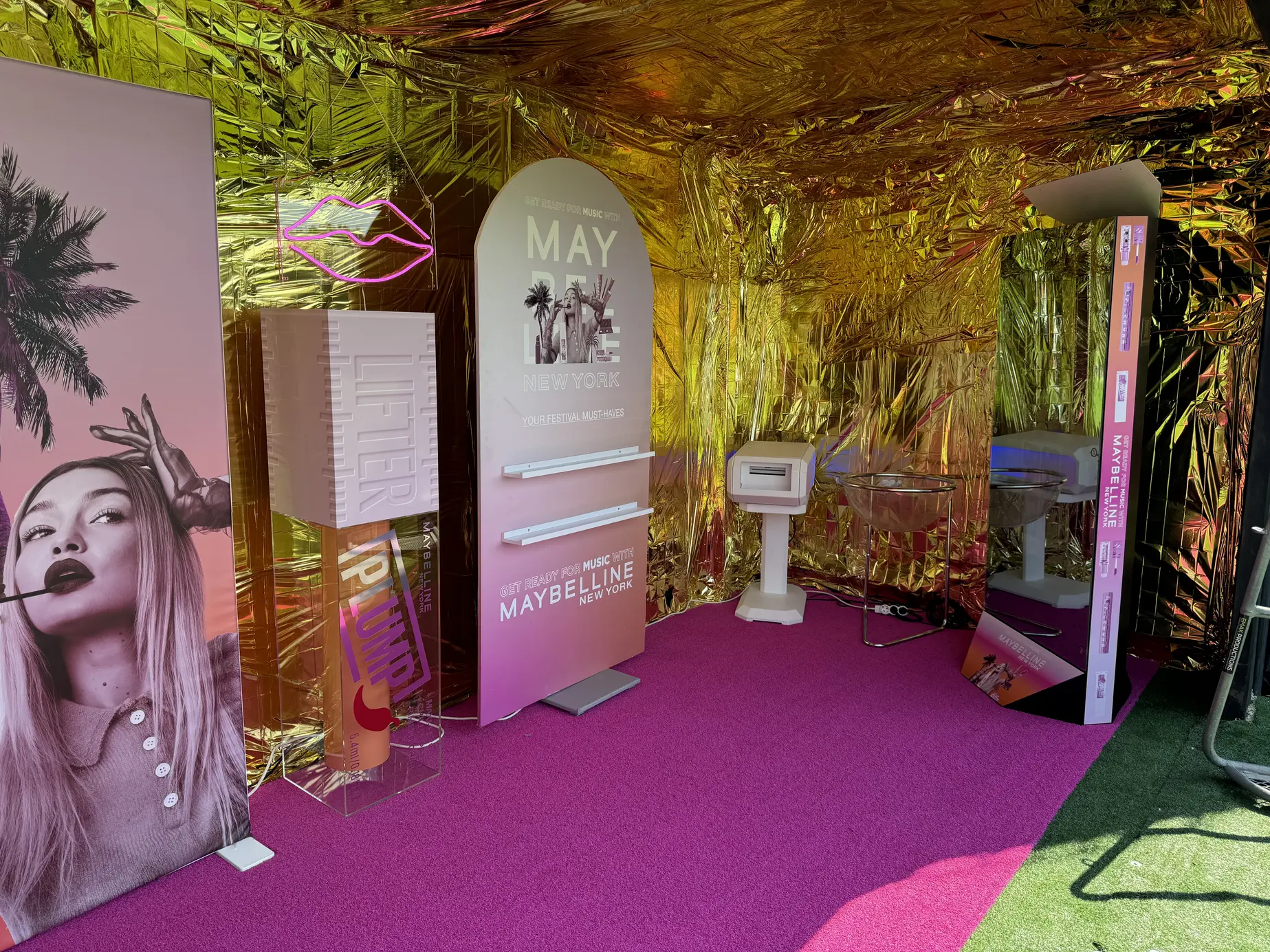 Gebrandeter Maybelline-Container am FM4 Frequency 2024: Magic Mirror X im weißen Bogenrahmen vor Goldfolie und magentafarbenem Teppich
